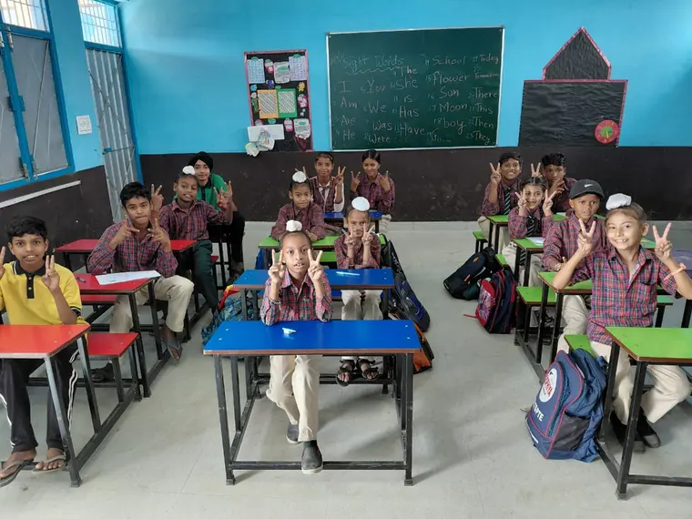 Students at their desks giving a peace sign