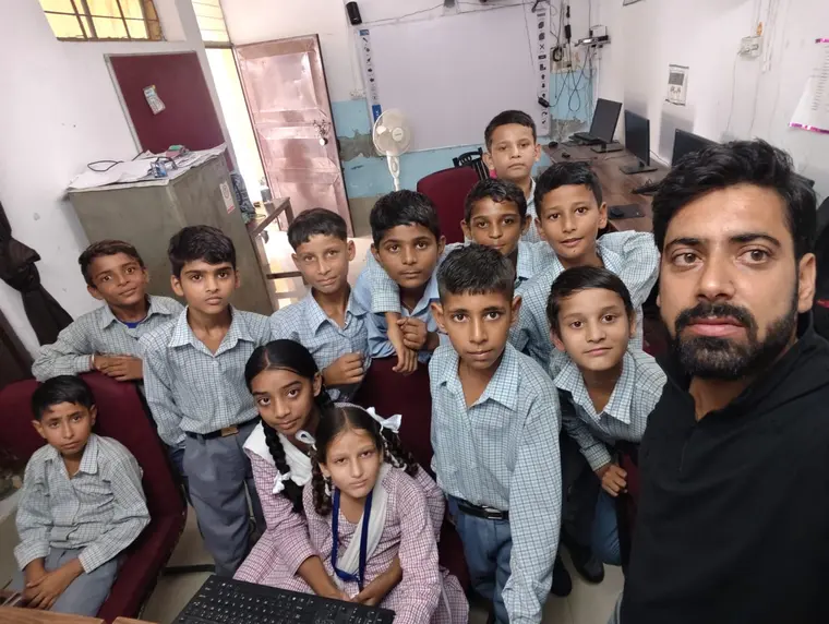 Facilitator and students gathered around a desktop computer