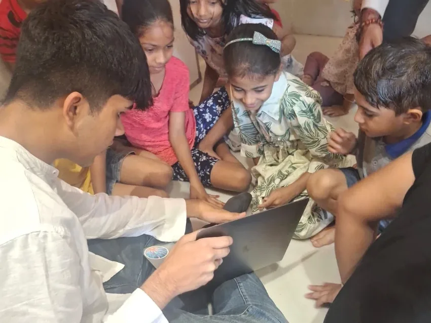 Children exploring a laptop with an Avana volunteer